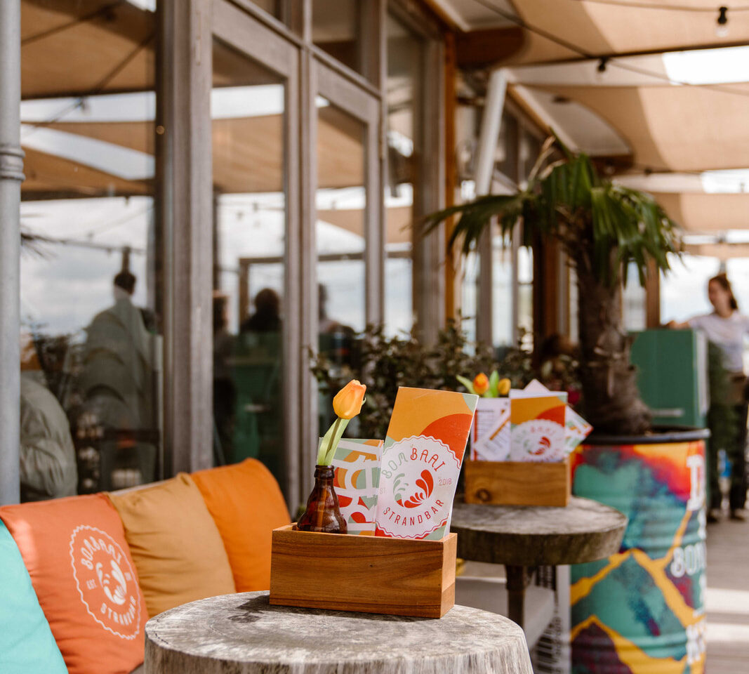 Buiten terras van Bombaai Strandbar met kleurrijke stoelen kussentjes
