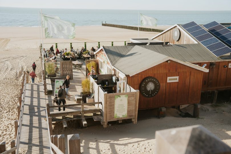Uitzicht vanaf de duinen over het strand en De Botanist aan Zee