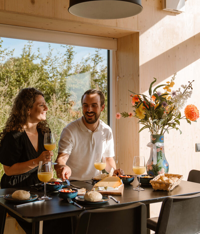 Koppel in Tiny House 16 op Buitenplaats Zeeuwse Liefde in Westkapelle aan de eettafel
