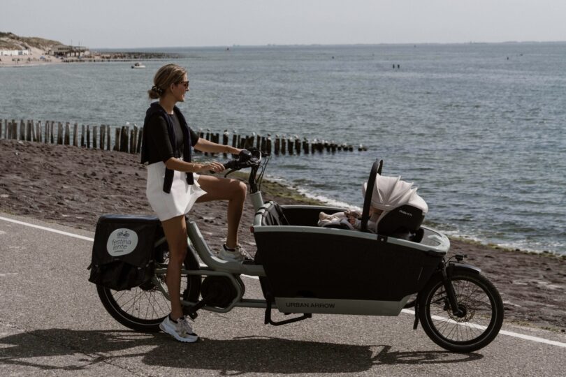 Moeder met elektrische bakfiets op het strand